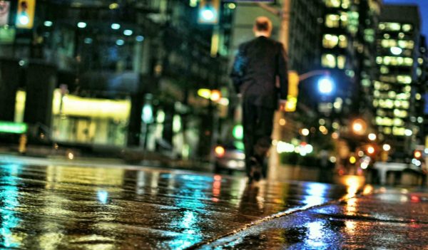 Man walking in the city in the rain at night