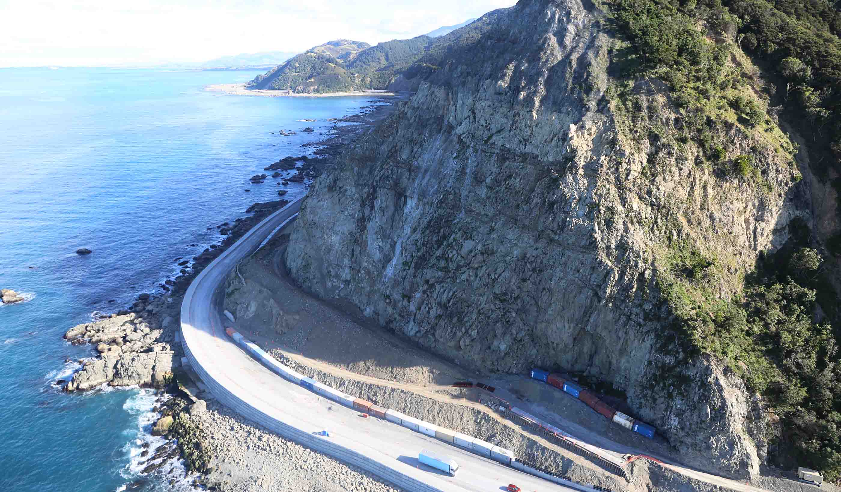 roadway in between a cliff and water